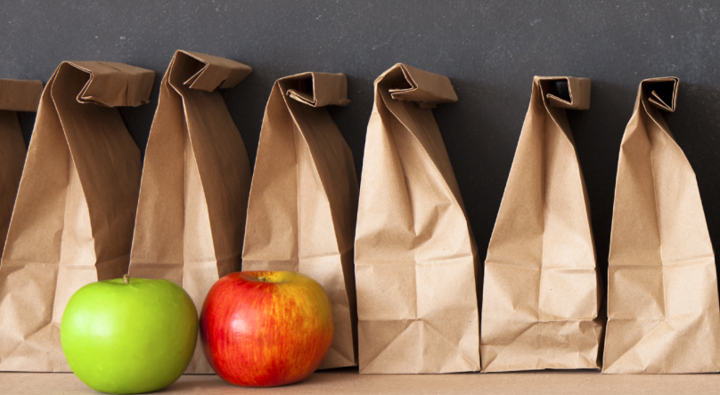 Lunch bags lined up with two apples in front